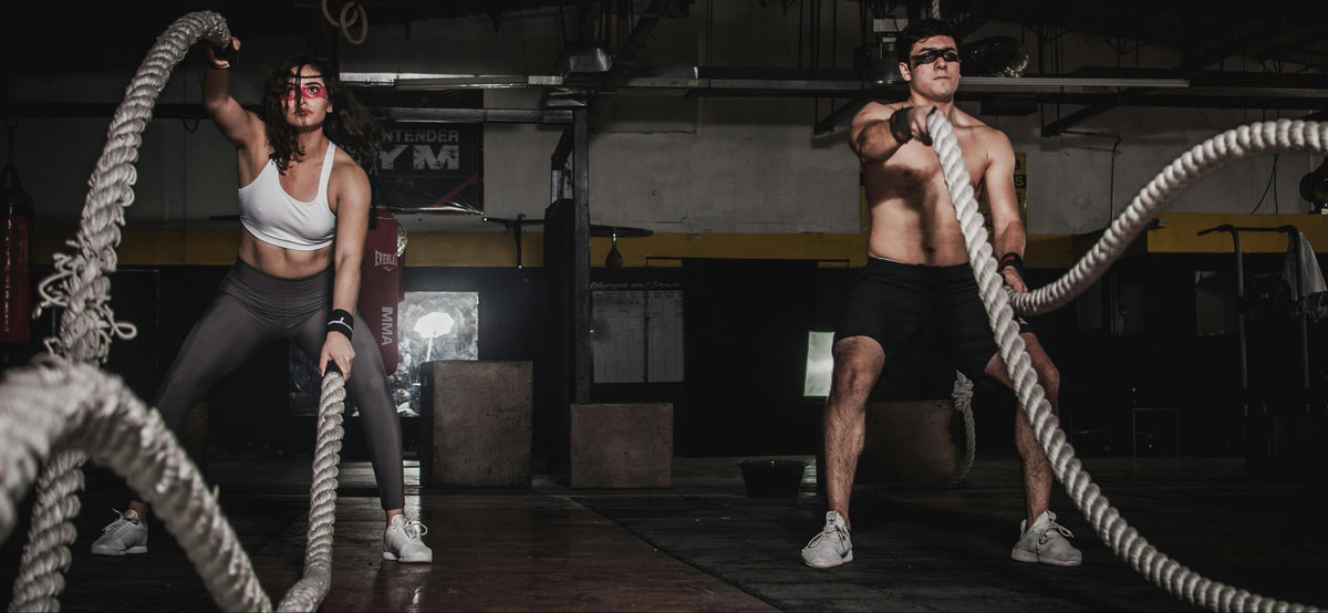 Two people using battle ropes in a gym setting